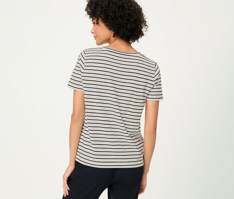 Vue arrière d'une femme aux cheveux bouclés portant un T-shirt Olsen à rayures noires et un pantalon noir.