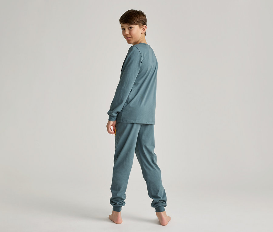 Garçon en pyjama bleu-vert à manches longues, vu de dos, regardant par-dessus son épaule vers la caméra.