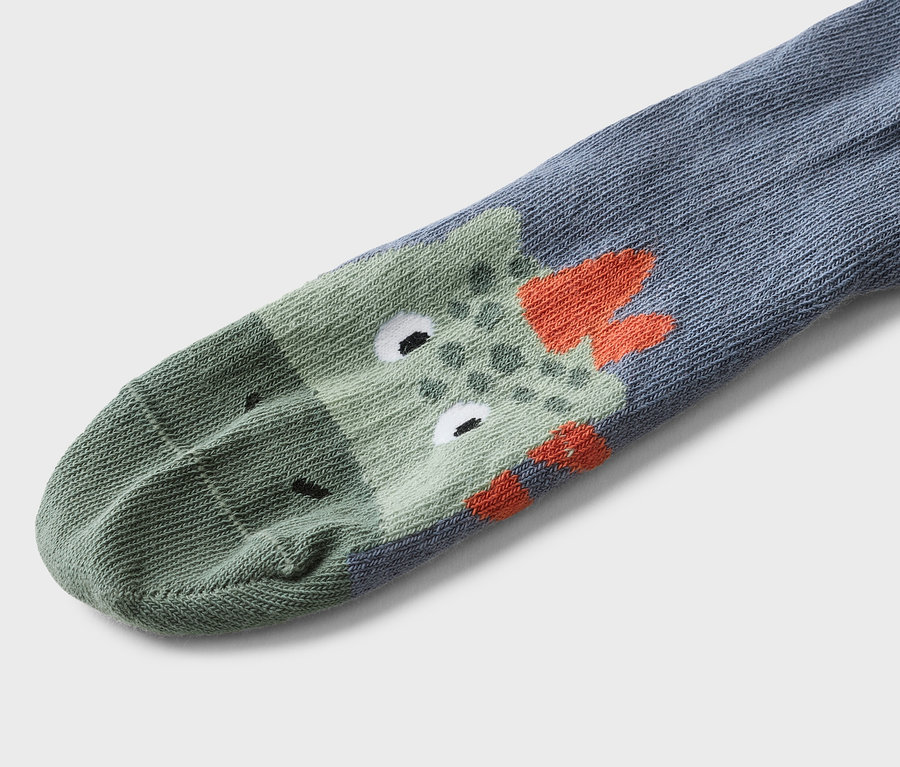 Gros plan d'une chaussette grise avec un motif de crocodile vert et des détails orange.