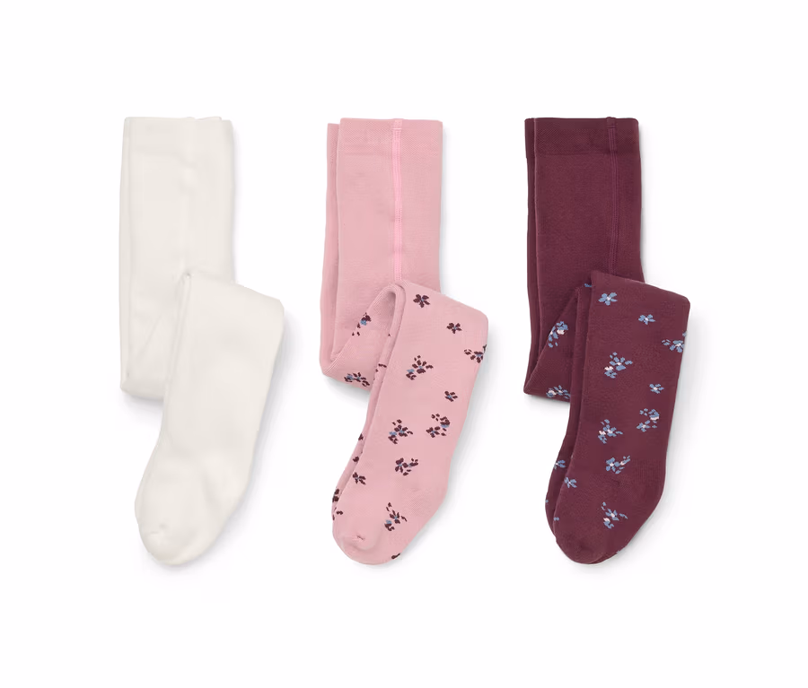 Trois paires de collants sur fond blanc : une blanche, une rose clair avec jambes à motif floral et une bordeaux avec jambes à motif floral.