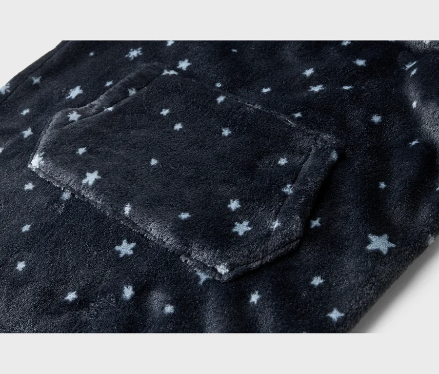 Gros plan d'un tissu en peluche bleu foncé avec des motifs d'étoiles bleues claires et blanches, incluant une poche.