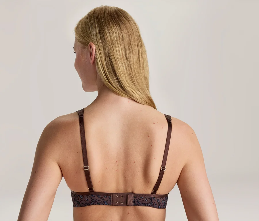 Vue de dos d'une femme aux longs cheveux blonds, portant un soutien-gorge marron avec un motif discret et des bretelles réglables.