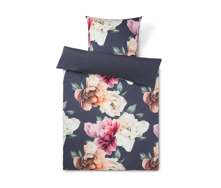 Parure de lit avec un fond bleu foncé et un grand motif floral de fleurs roses, pêche et crème avec des feuilles vertes. La housse de couette est pliée, révélant un dessous uni bleu foncé, avec une taie d'oreiller assortie placée au-dessus.