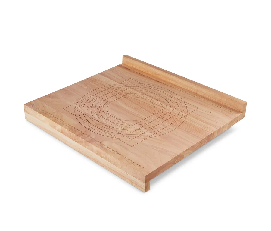 Une planche à pâtisserie en bois avec des cercles et des rectangles marqués pour travailler la pâte.