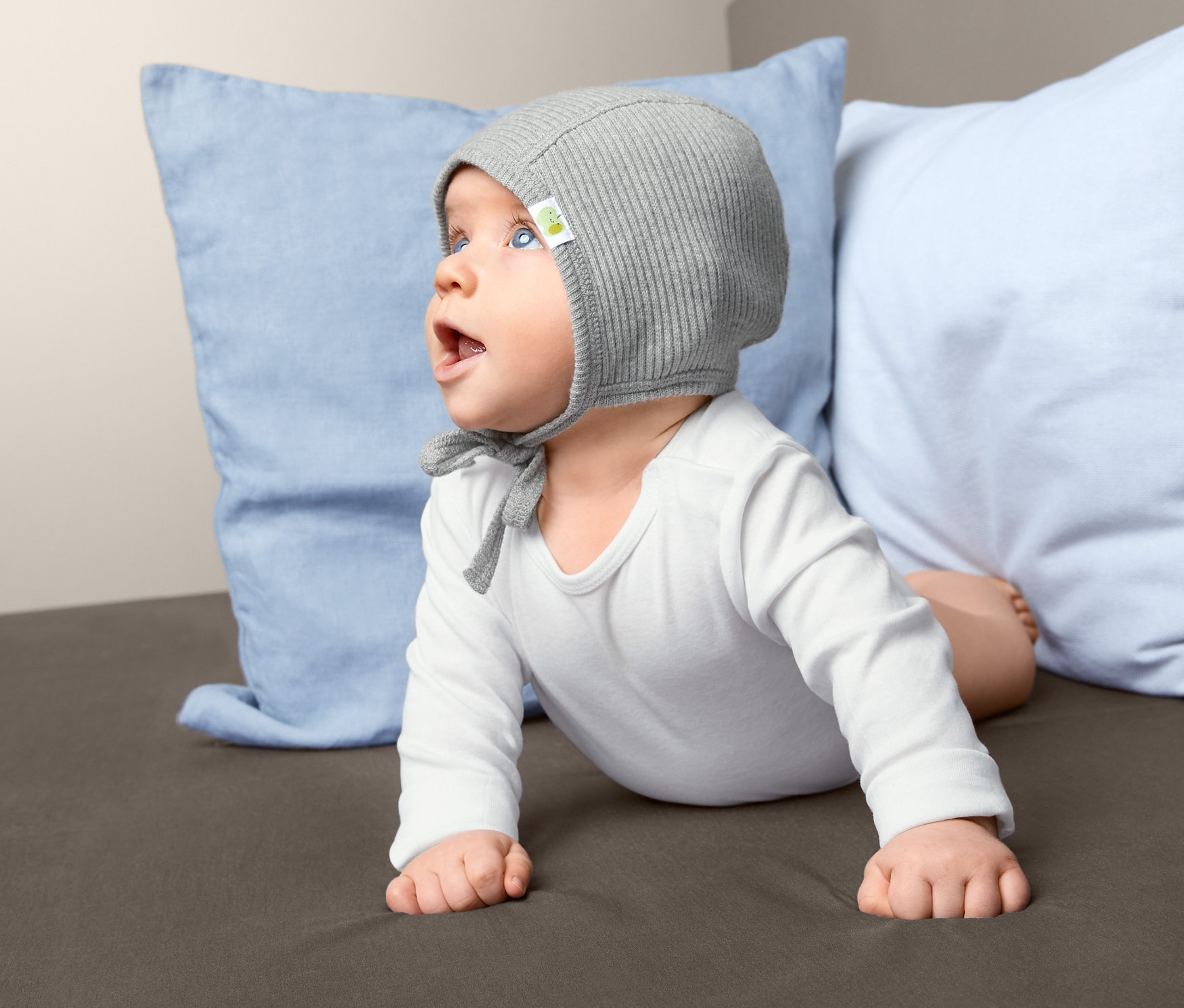 Bébé allongé sur le ventre portant un bonnet.