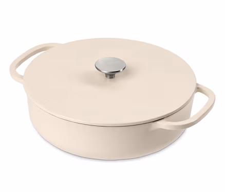 Une cocotte basse en fonte couleur crème avec couvercle et poignée argentée.