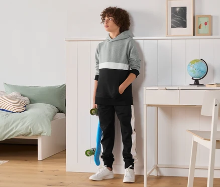 Garçon debout dans une chambre portant un ensemble molletonné, 2 pièces.