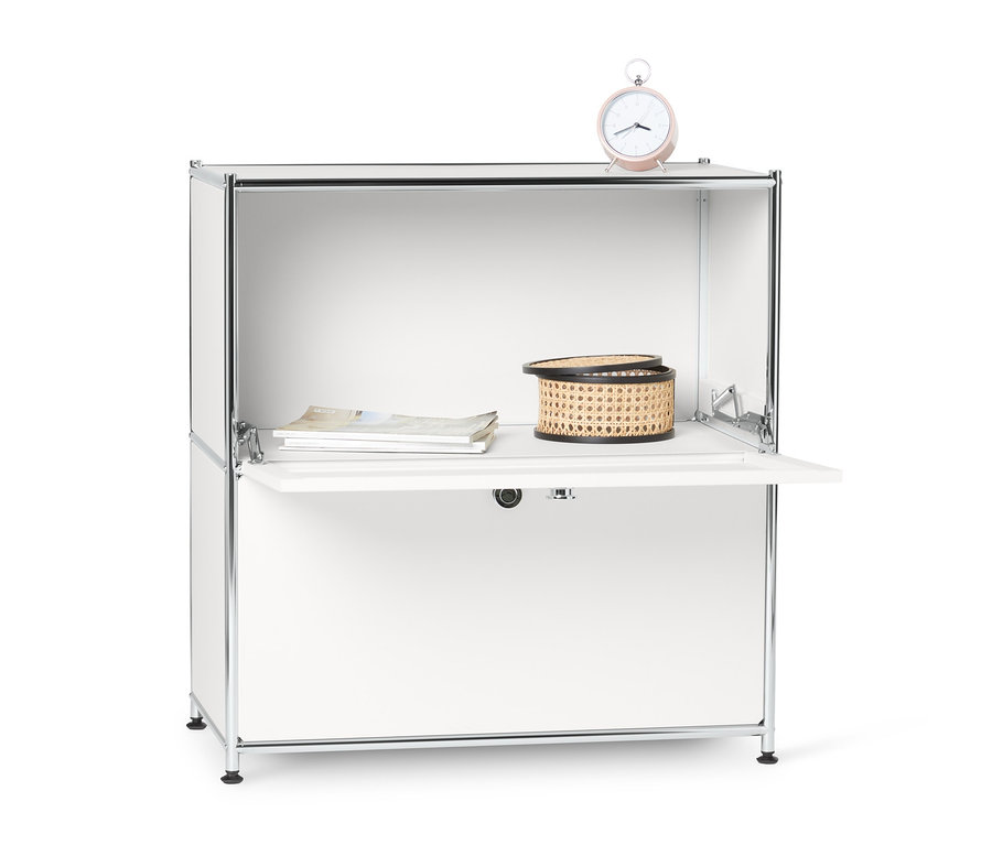 Petit buffet en métal « CN3 » blanc à abattants avec une horloge, un panier et des magazines dessus.