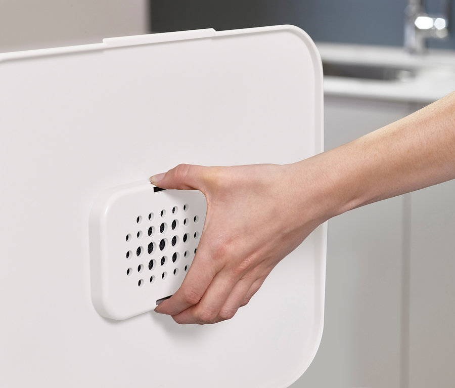 Une main tient un filtre blanc de la poubelle de tri sélectif Joseph Joseph.