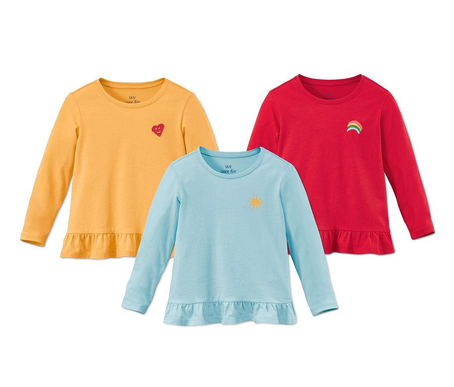 Trois t-shirts à manches longues en coton bio : un jaune avec un cœur, un bleu avec un soleil et un rouge avec un arc-en-ciel.