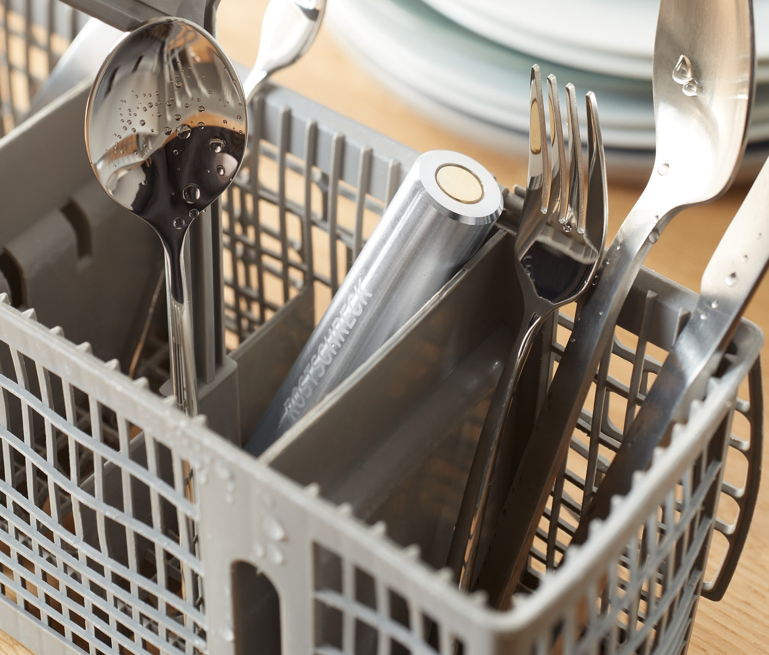 Des couverts argentés dans un panier à couverts gris avec un antirouille pour lave-vaisselle.