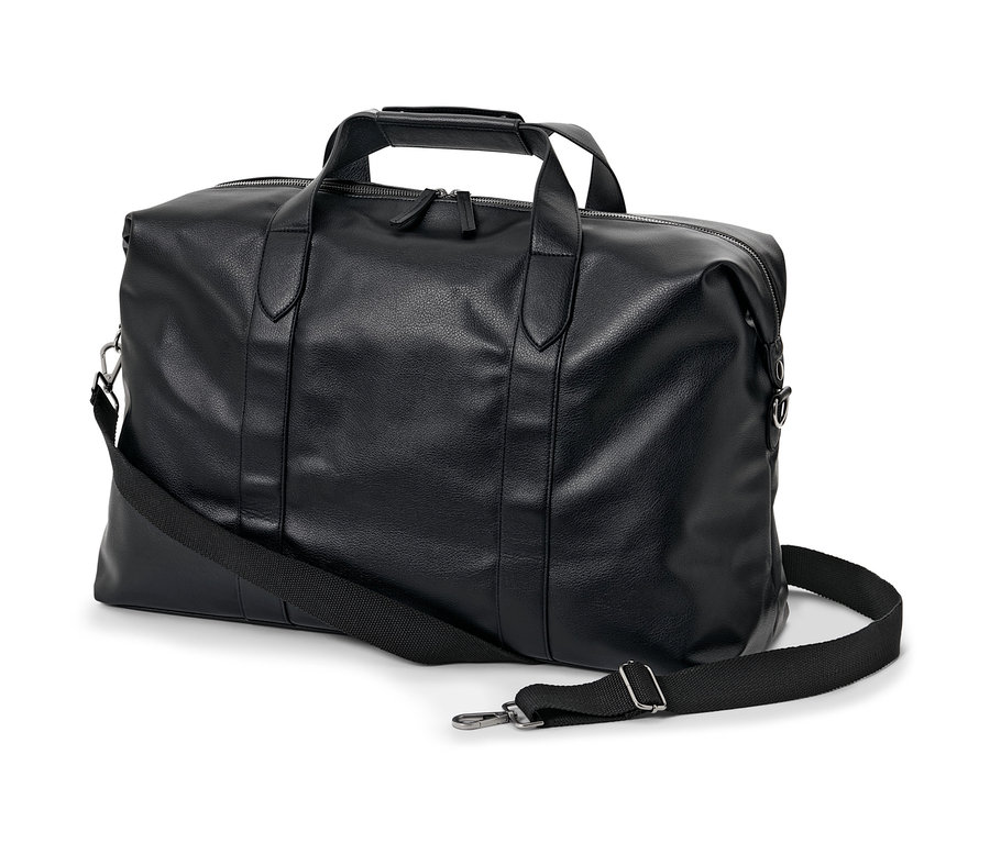 Un sac week-end noir avec une bandoulière posé sur un fond blanc.