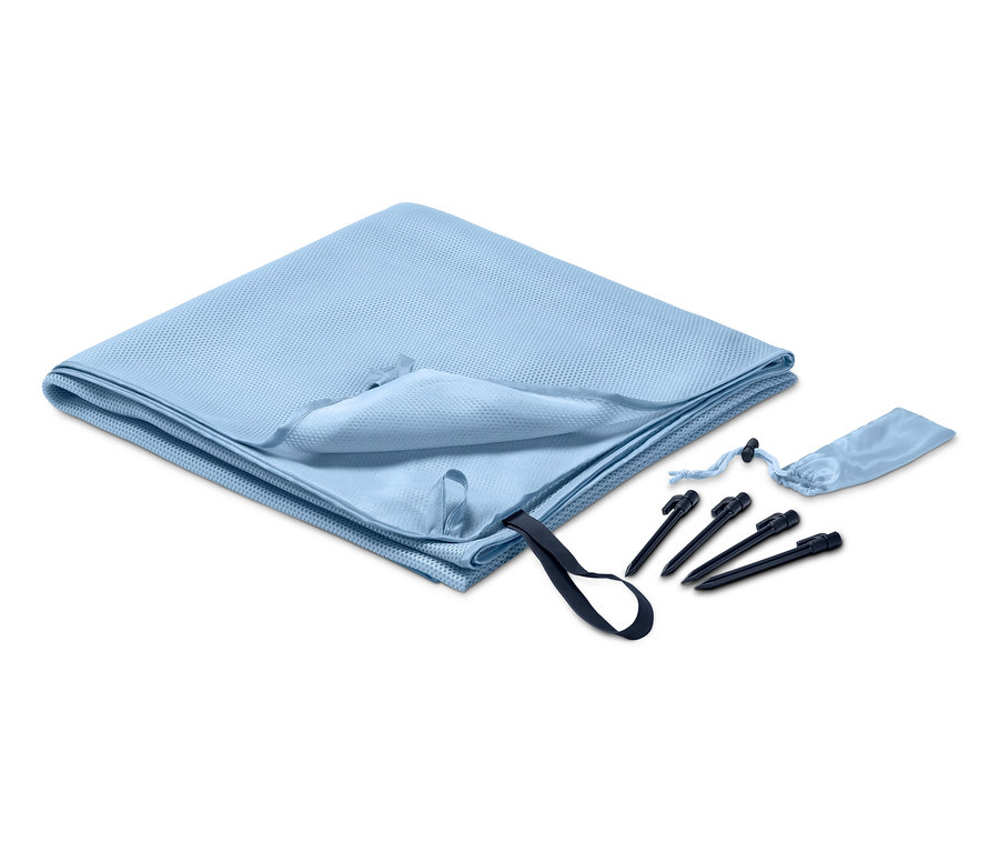 Couverture de plage anti-sable bleu clair pliée à côté de piquets et d'un étui.