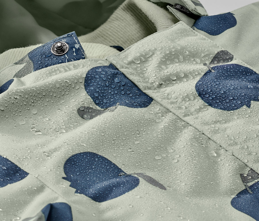 Gros plan sur une combinaison de pluie pour tout-petit avec des gouttes d'eau et un motif bleu.