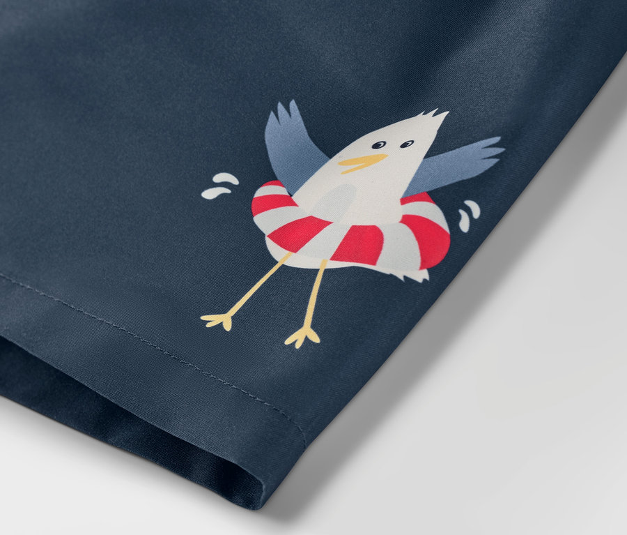 Gros plan sur un boardshort pour enfant avec un motif marin, imprimé d'une mouette dans une bouée de sauvetage.