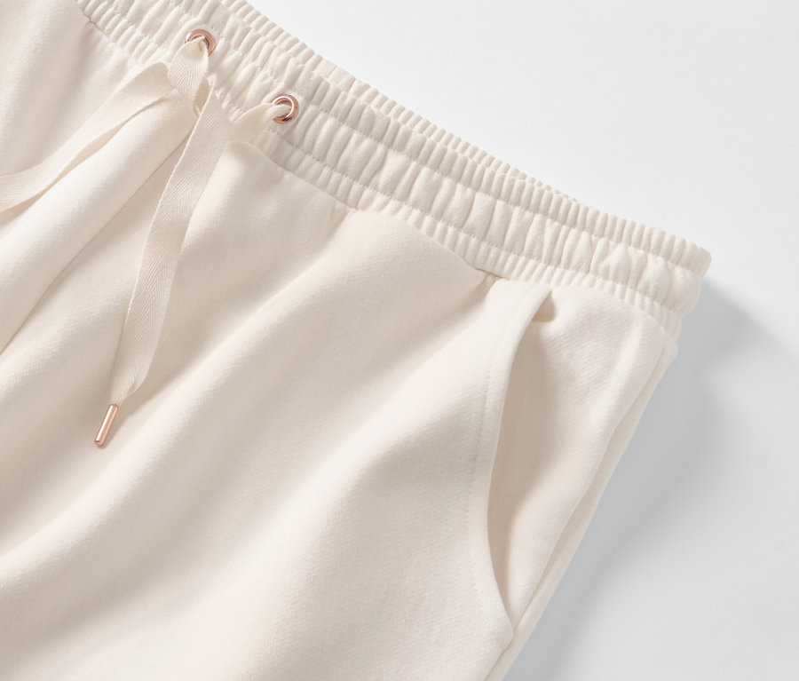 Détail d'un pantalon de survêtement d’intérieur crème avec taille élastique et cordon de serrage.