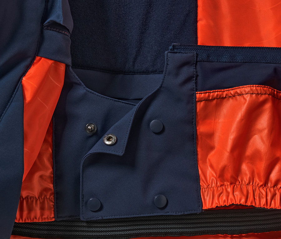 Gros plan sur une veste de ski high-tech avec une doublure orange et une fermeture à boutons-pression.