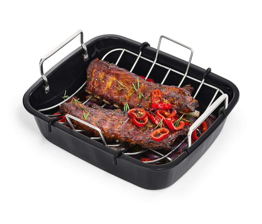 Deux morceaux de viande rôtie avec du paprika et des herbes dans une rôtissoire XL en acier inoxydable avec gril.