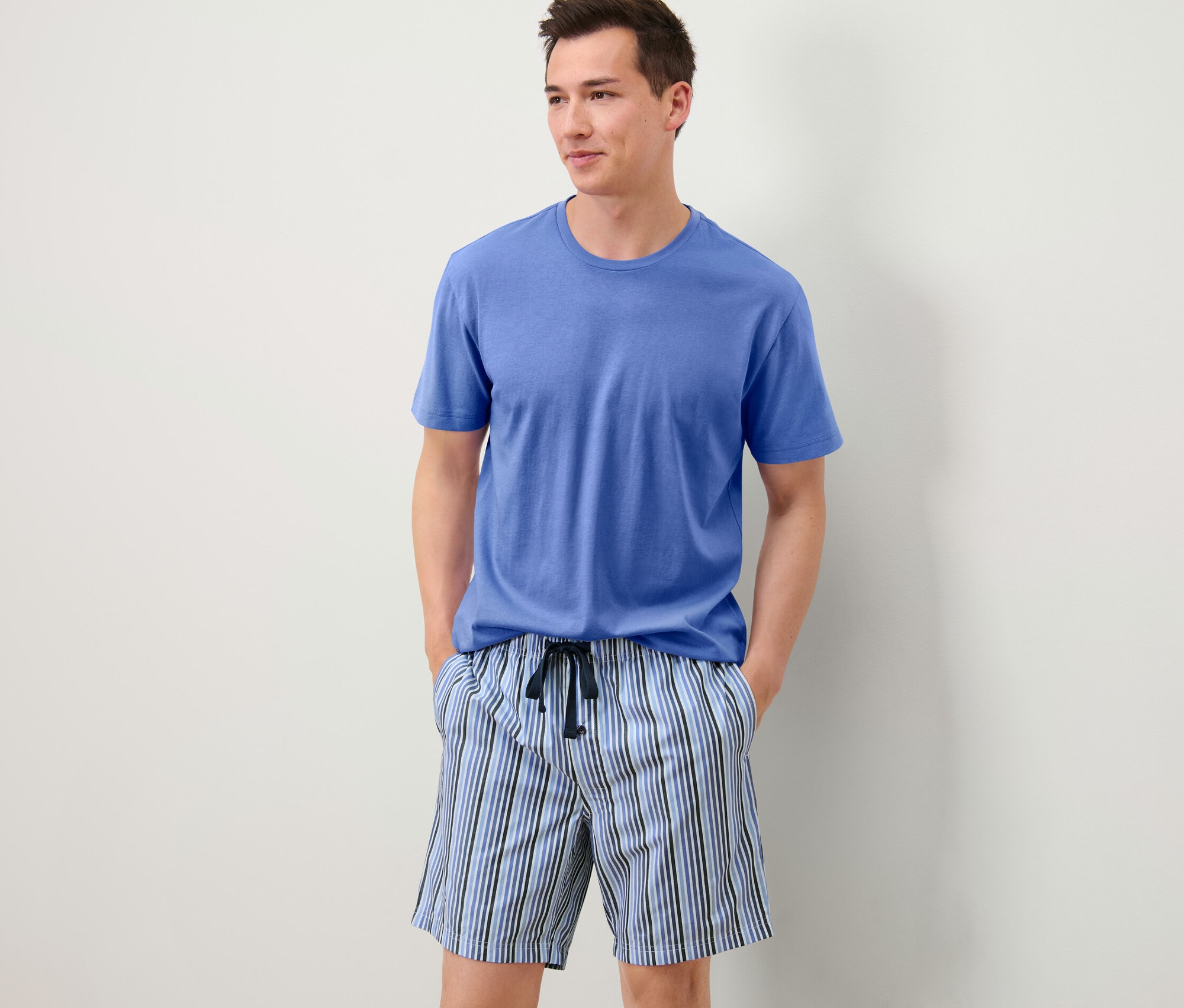 Homme portant un pyjashort avec un t-shirt bleu et un short rayé.