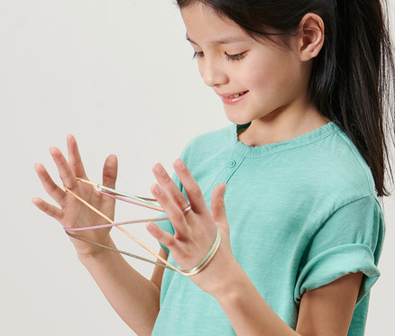 Une fille joue au Fingertwist, lot de 2, avec la ficelle sur les mains.