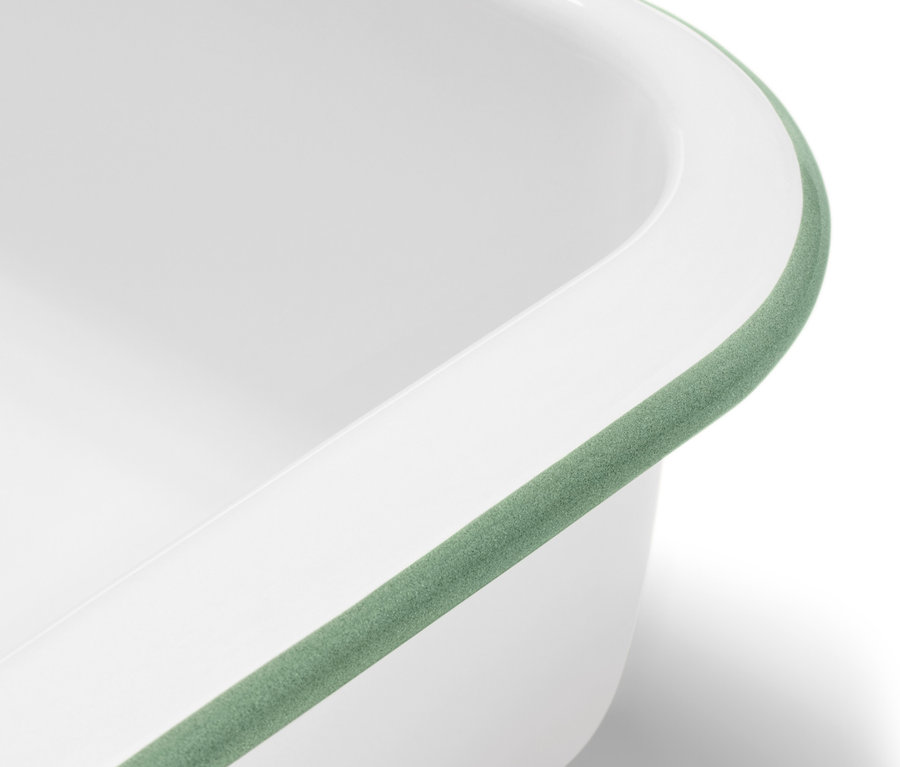 Gros plan sur un moule à gratin en émail blanc avec couvercle et bordure verte.