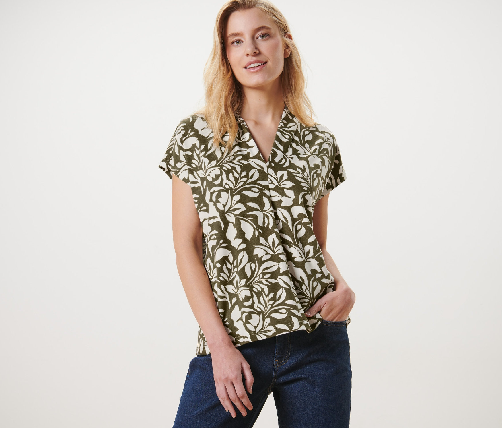 Femme posant en blouse imprimée avec encolure en V et jean.