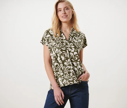 Femme posant en blouse imprimée avec encolure en V et jean.