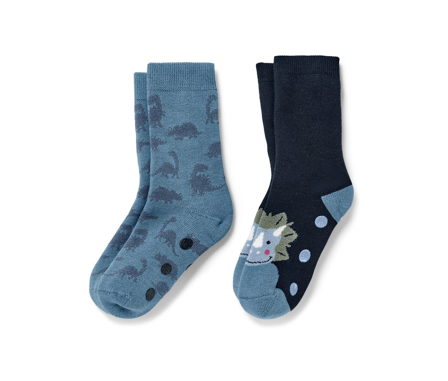 Deux paires de chaussettes antidérapantes pour enfant : une paire bleue avec des dinosaures, une paire bleu marine avec un tricératops.