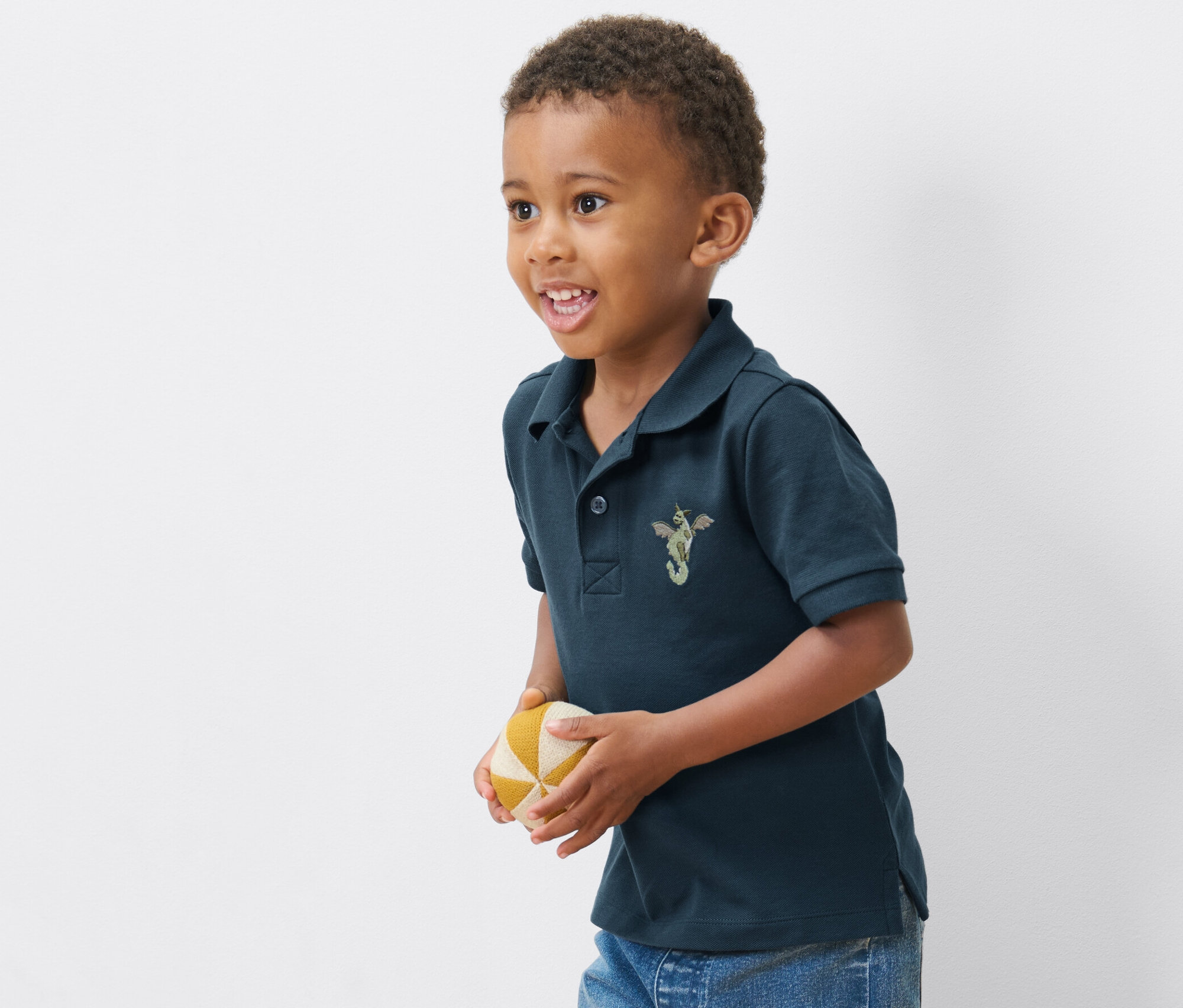 Garçon portant l'un des 2 polos pour enfant en piqué de coton et tenant un ballon.