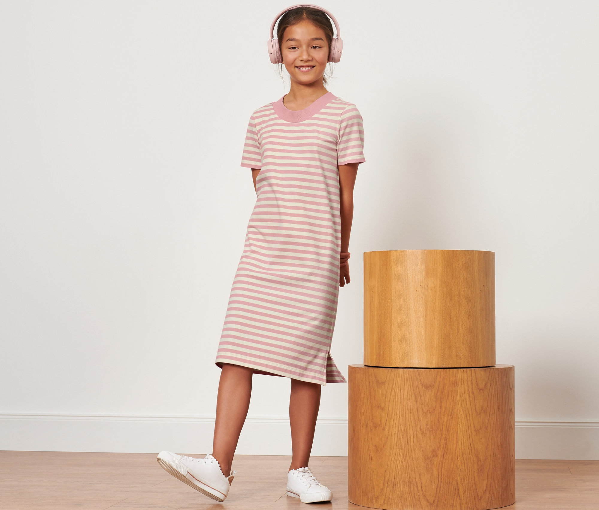 Fille avec un casque rose debout dans une robe en jersey rayée pour enfant.