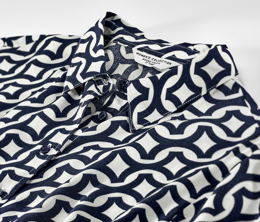 Gros plan sur une robe chemise imprimée avec un motif géométrique bleu et blanc.