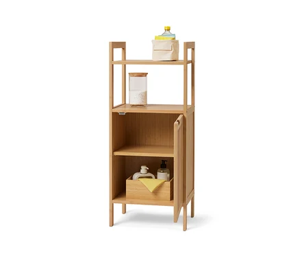 Étagère de rangement verticale de style scandinave avec des étagères ouvertes et une porte, sur laquelle sont stockés des conteneurs et des textiles.