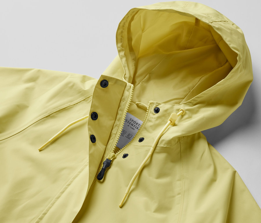 Veste de pluie jaune avec capuche, fermée par une fermeture éclair et des boutons-pression.