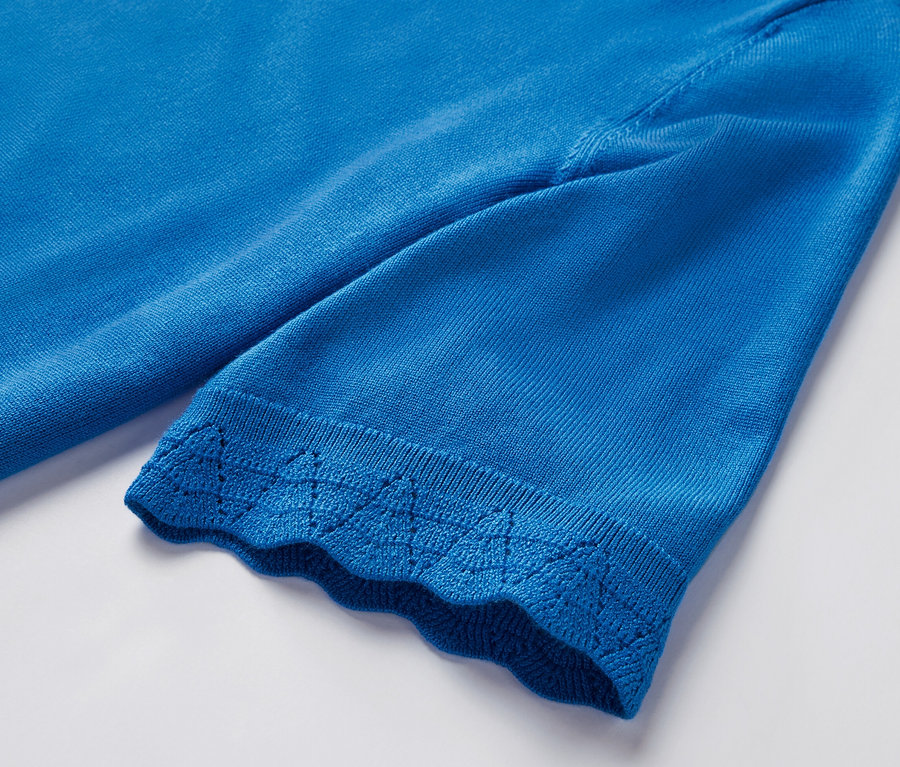 Détail d'un pull en maille fine bleu cobalt à manches courtes avec une bordure décorative.