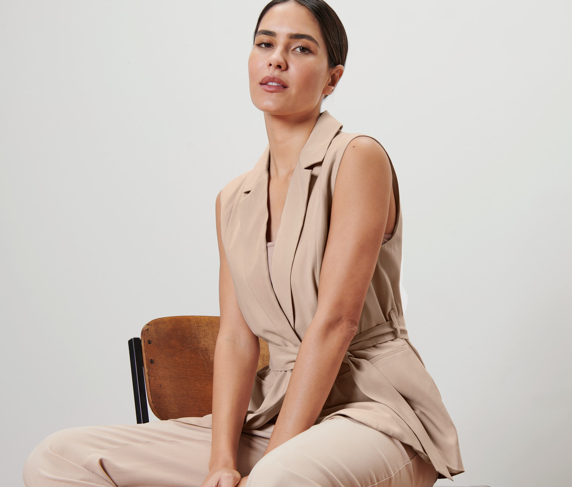 Une femme est assise sur une chaise et porte un gilet avec une ceinture à nouer.