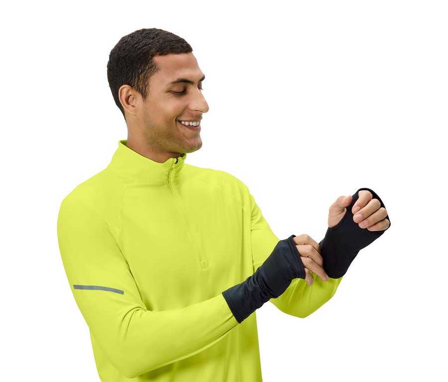 Un homme ajuste ses manchettes noires, il porte un haut jaune-vert.