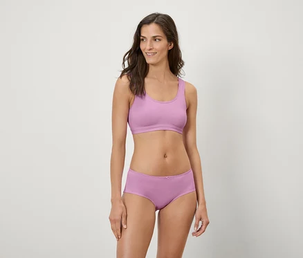 Femme posant en soutien-gorge de sport lilas et boxer.