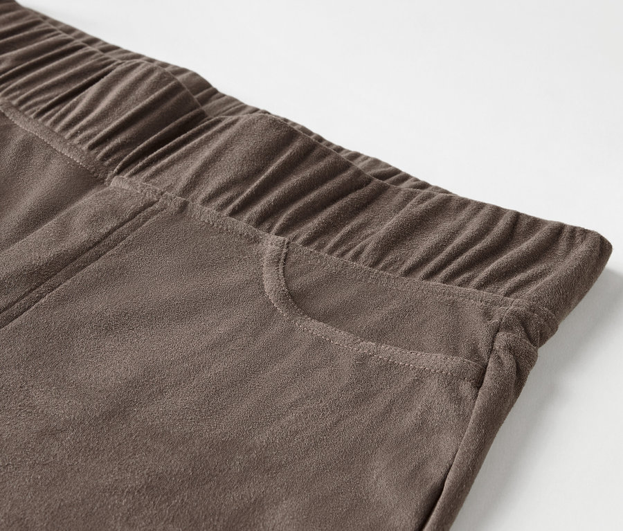 Détail d'un pantalon marron avec une taille élastique et une poche.