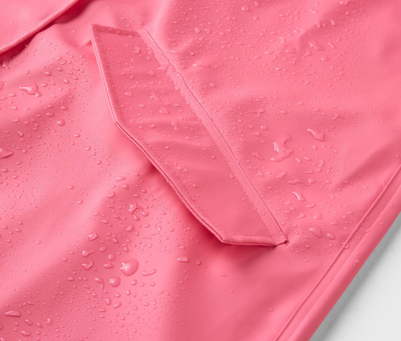 Gros plan sur un manteau de pluie rose avec des gouttes d'eau.