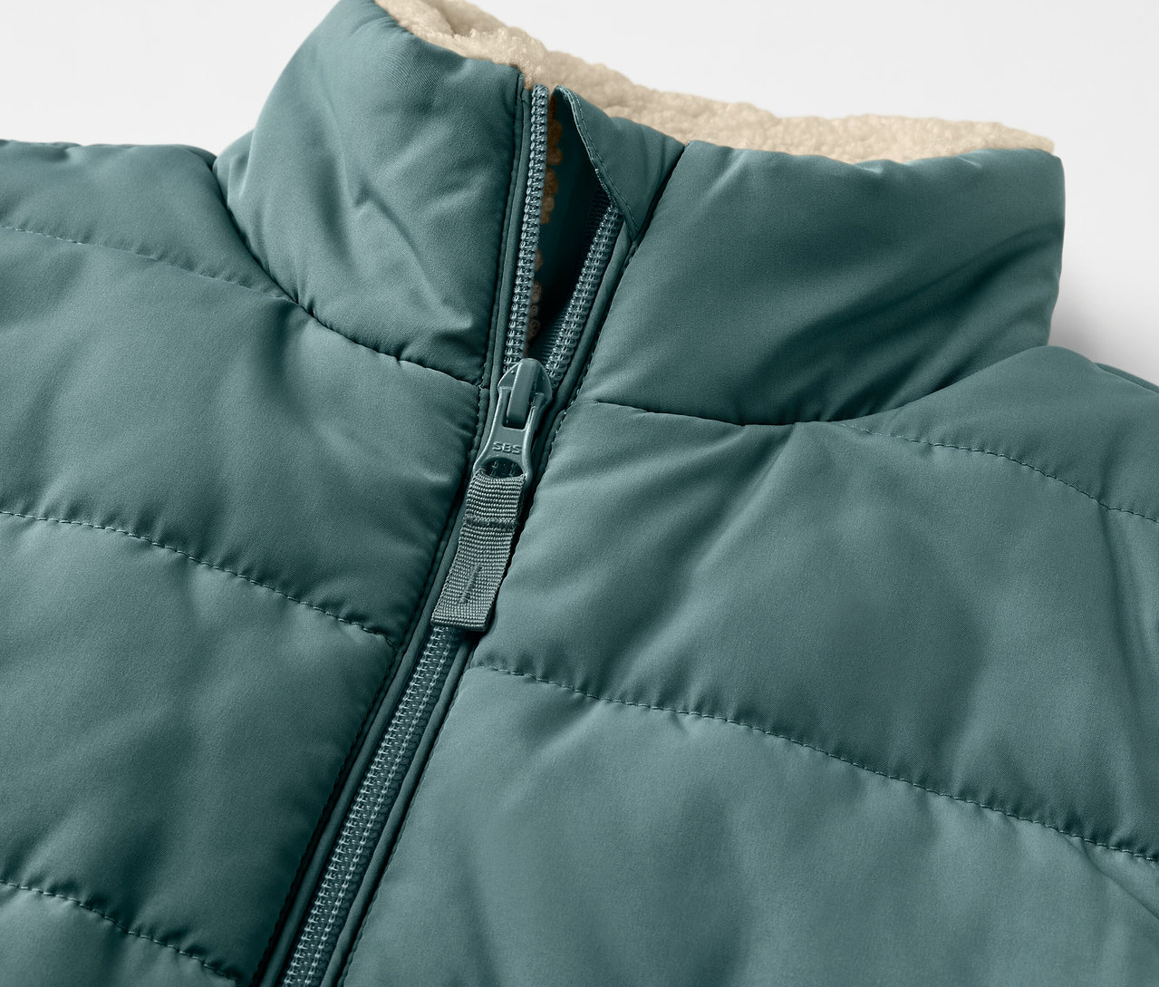 Détail d'un gilet sans manches matelassé en teddy pour enfant avec fermeture éclair.