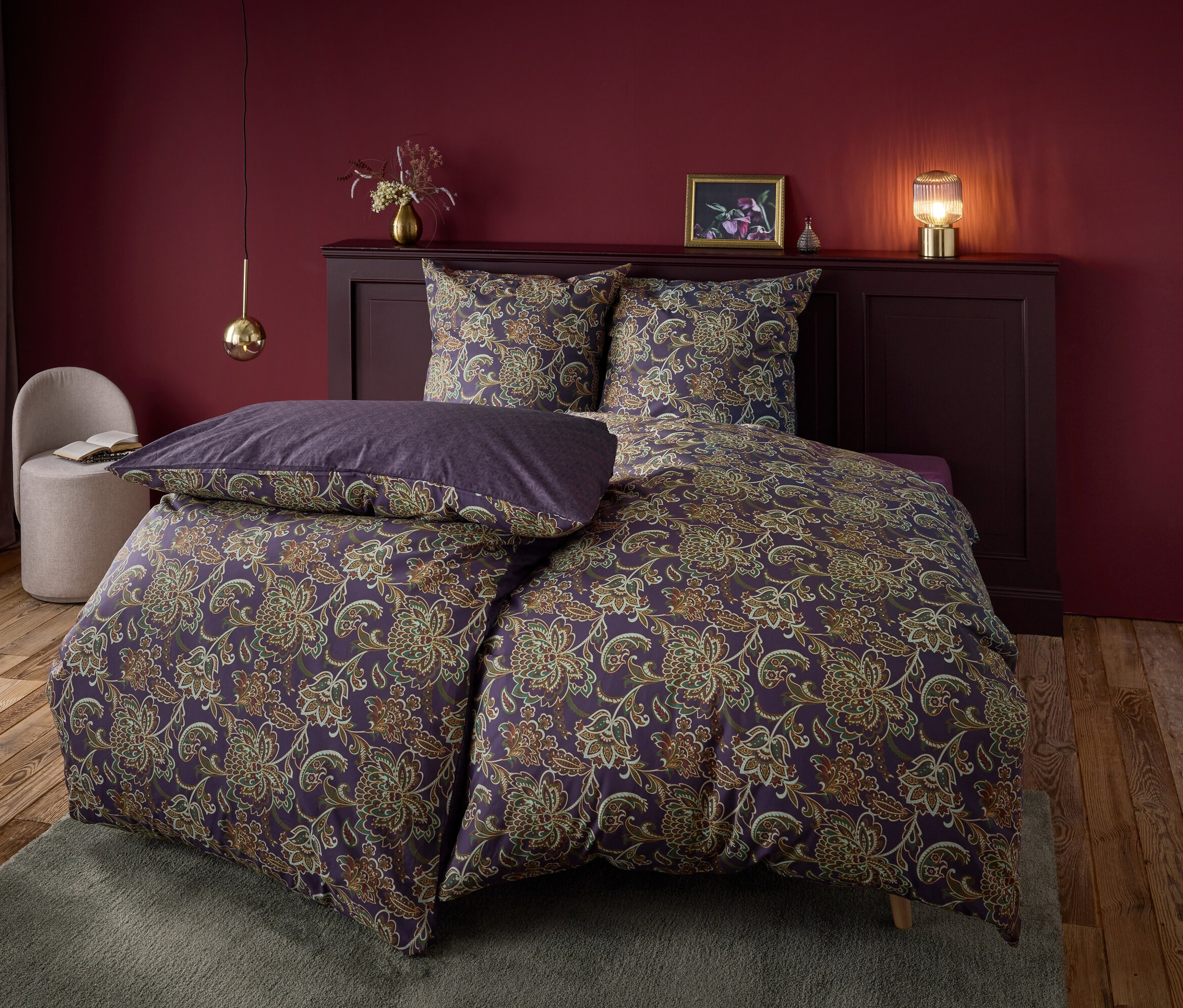 Linge de lit floral violet sur un lit avec une tête de lit violette et une table de chevet sur un fond rouge foncé.