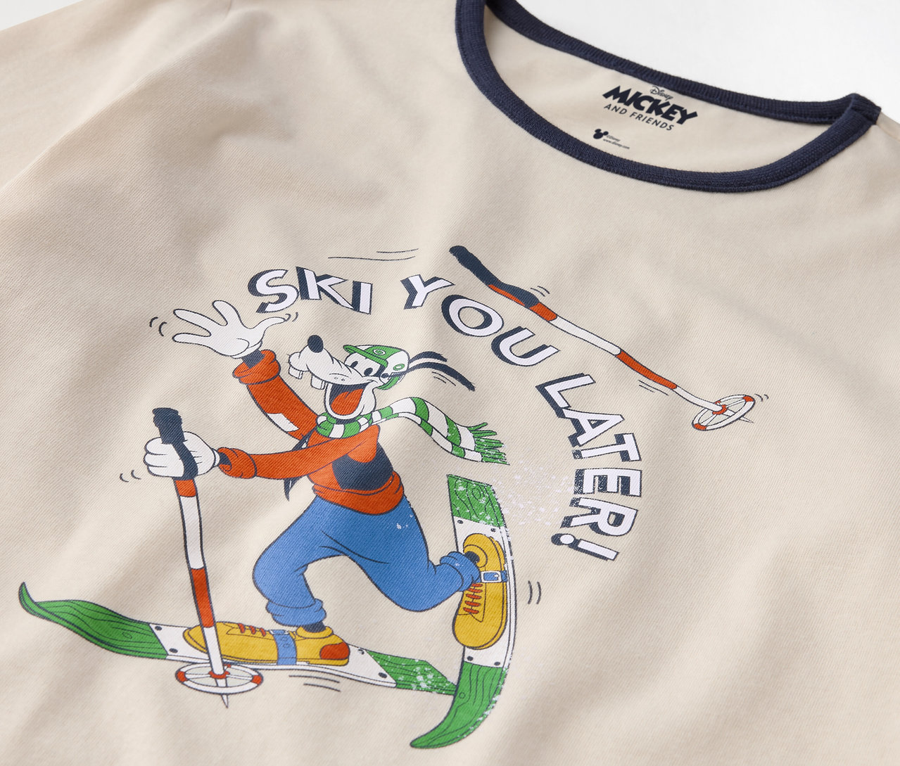 Détail d'un t-shirt en coton avec un imprimé de Goofy faisant du ski et l'inscription "Ski you later !".