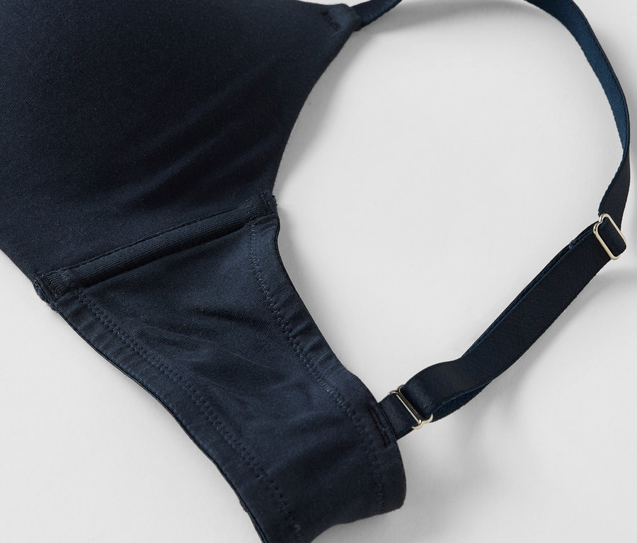 Gros plan d'un soutien-gorge bleu marine avec bretelles réglables sur fond blanc.