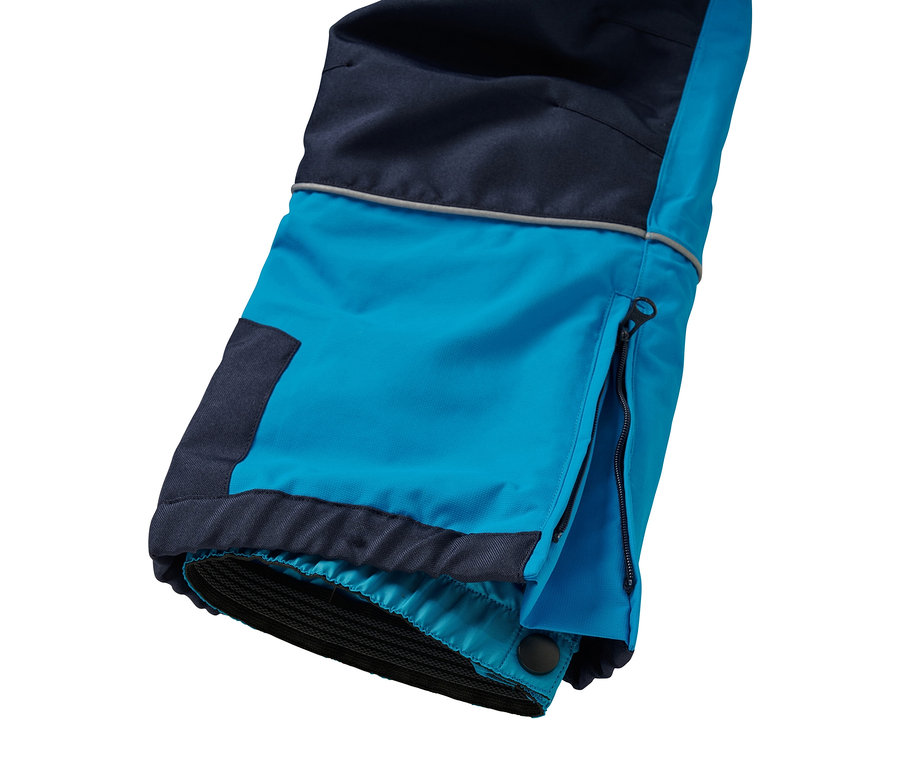 Détail d'un pantalon de ski bleu et bleu foncé avec une fermeture éclair ouverte sur le côté.