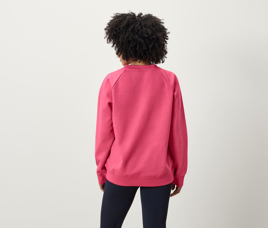Vue arrière d'une femme avec une coiffure afro portant un sweat-shirt rose et un pantalon bleu marine.