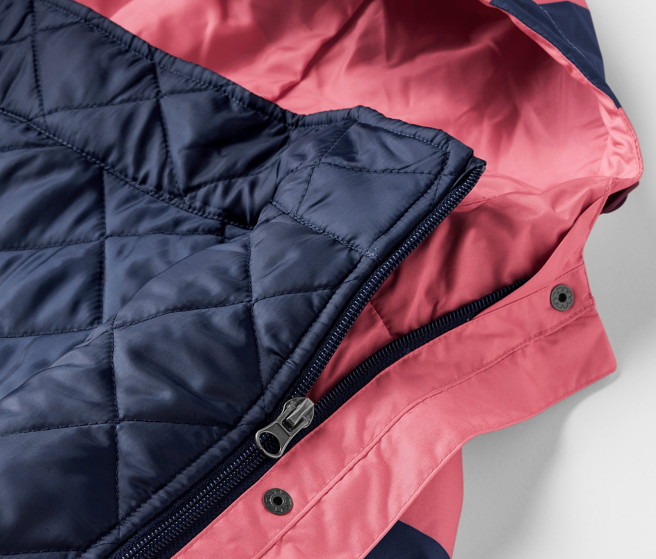 Gros plan sur une veste de pluie 3 en 1 rose et marine avec capuche.