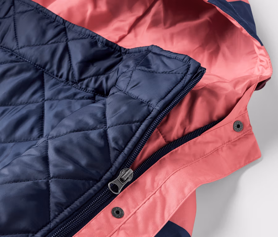 Gros plan sur une veste de pluie 3 en 1 rose et marine avec capuche.