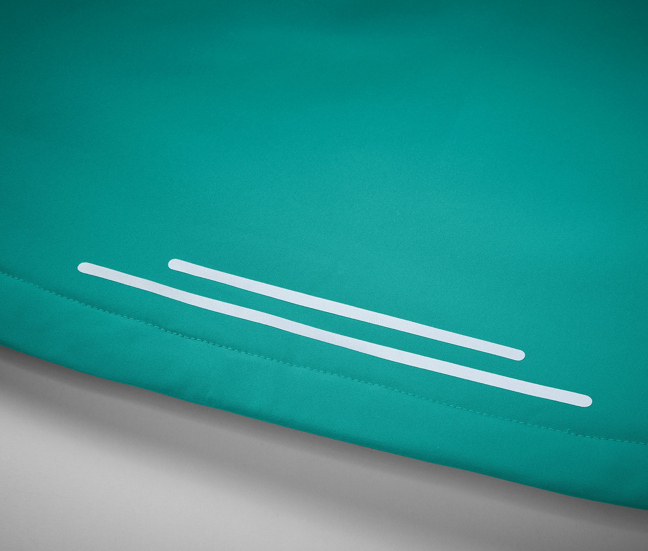 Gros plan d'un tissu turquoise avec deux bandes réfléchissantes blanches.