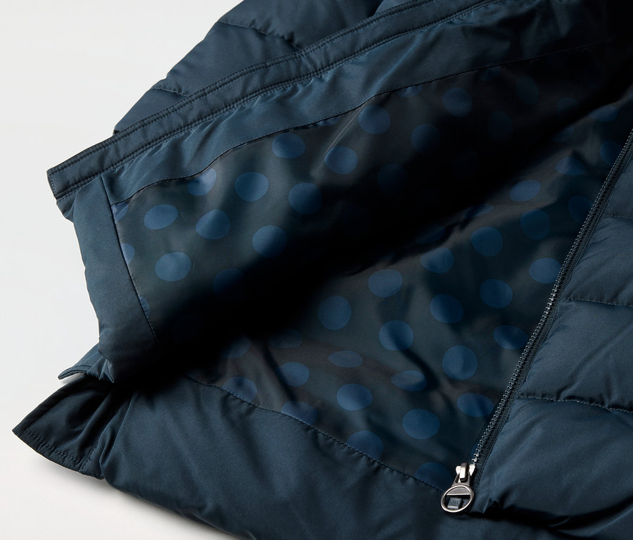 Gros plan sur un manteau thermique pour enfant avec une doublure bleue à pois et une fermeture éclair.