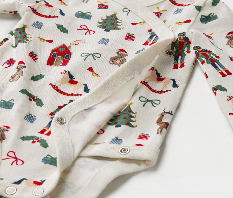 Détail d'un body en coton avec des motifs de Noël et des boutons-pression.